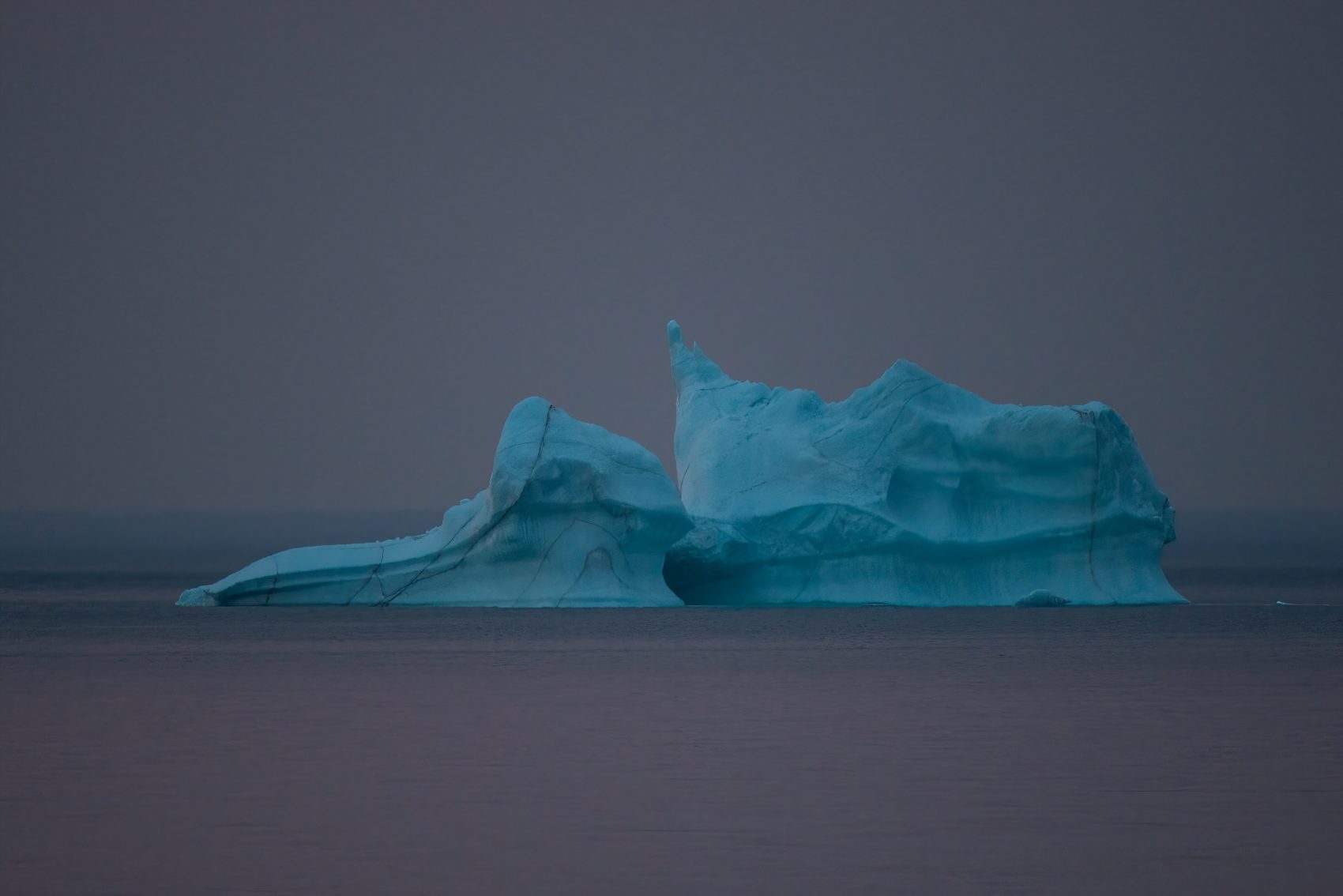 A photo of an iceberg floating of the ocean.