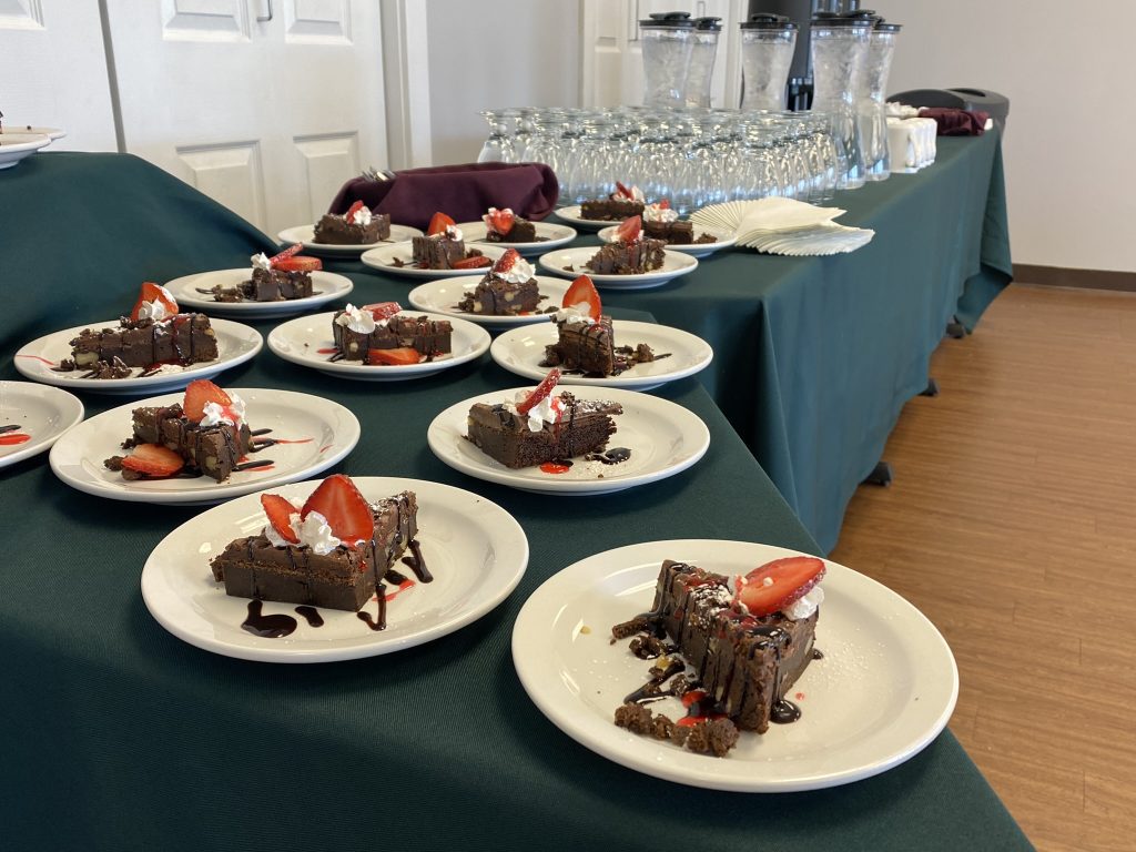 Chocolate cake with whip cream, strawberries, and chocolate sauce are plated on a table in the Provincial Learning Centre.